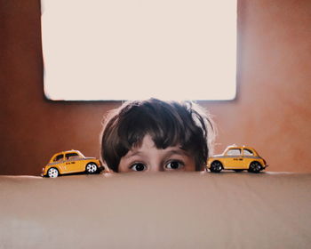 Cropped portrait of boy with toy cars on sofa