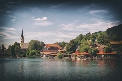 Scenic view of river by buildings against sky