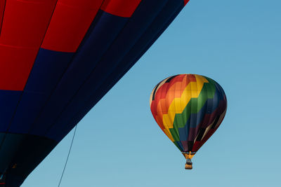 Low angle view of colorful hot air balloons flying against clear blue sky