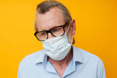 Senior man wearing mask against yellow background