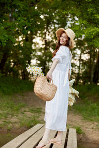 Portrait of young woman wearing hat while standing against plants