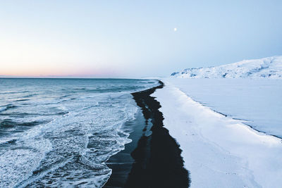 Overhead aerial shot of beautiful black beach in iceland in winter with snow