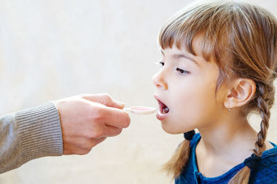 Hand feeding medicine to girl