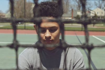 Boy seen through net at tennis court