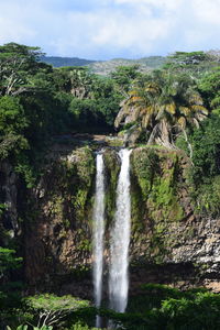 Scenic view of waterfall in forest against sky