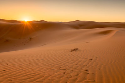 Scenic view of desert against sky during sunset