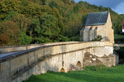 Arch bridge over river amidst trees and buildings