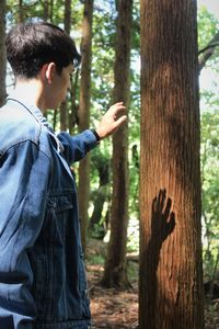 Side view of young woman standing in forest