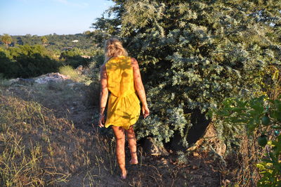 Young woman walking along trees