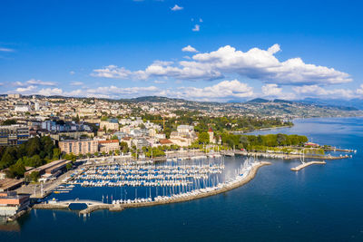 Aerial view of townscape by sea against blue sky