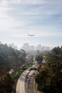 Airplane flying over city against sky