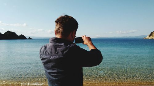 Rear view of man photographing at beach