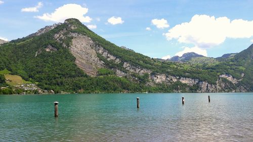 Scenic view of sea by mountain against sky