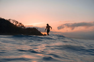 Full length of man standing at beach against sky during sunset