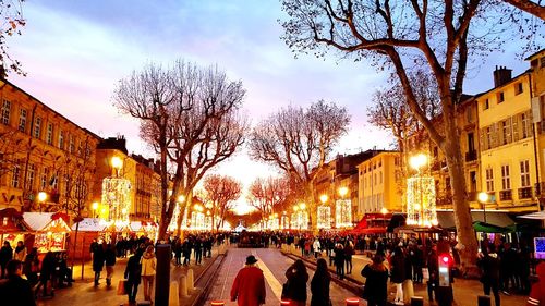 People on street amidst buildings in city at dusk