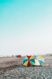Colorful umbrellas on beach against clear sky