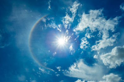 Low angle view of sunlight streaming through clouds