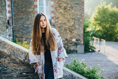 Young woman standing against wall