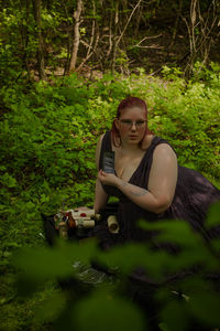 Portrait of young woman using mobile phone while sitting in park