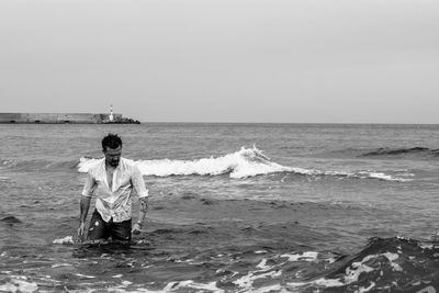 Man standing in sea against clear sky