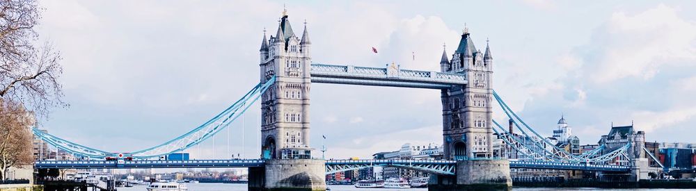 Low angle view of suspension bridge against cloudy sky