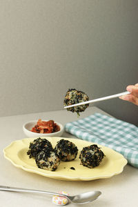 Female hand eat jumeokbap korean seaweed rice ball with kimchi. copy space for text