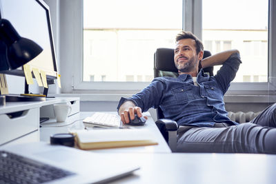 Relaxed man sitting at desk in office looking at computer screen