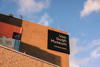 Low angle view of sign board against blue sky