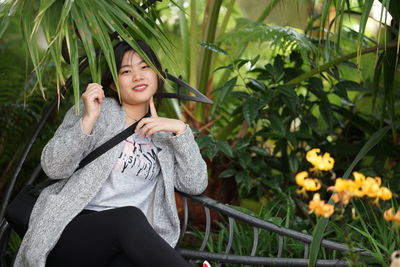 Portrait of young woman sitting on seat at park