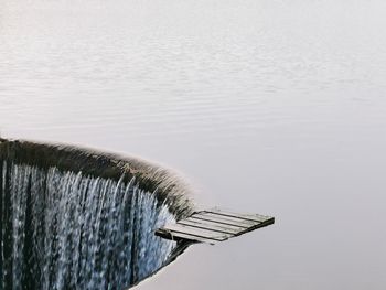 High angle view of water flowing by lake against sky