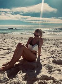 Portrait of woman sitting at sandy beach