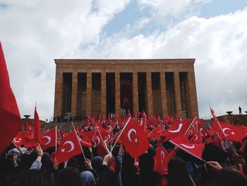 Crowd of people holding turkish flag against building