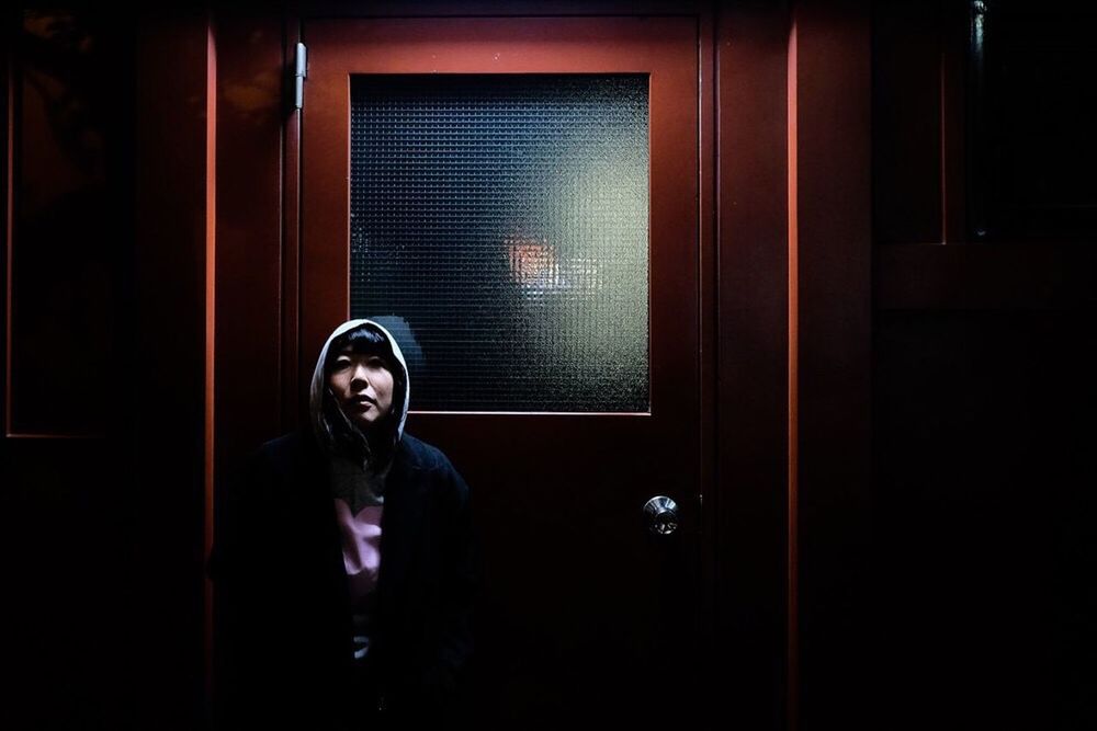 PORTRAIT OF YOUNG MAN STANDING AGAINST DOOR AT NIGHT