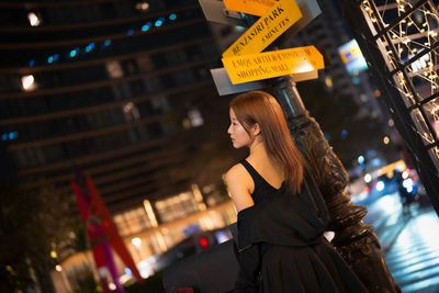 Portrait of young woman standing in city at night