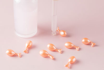 Transparent bottle of cosmetic or essential oil, aromatherapy with natural cosmetics. pink capsules 