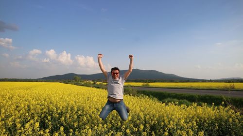 Portrait of happy man jumping on land against sky