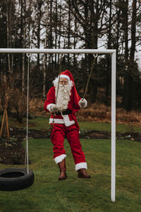 Man wearing santa costume swinging in garden