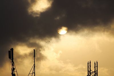 Low angle view of repeater towers against dramatic sky at dusk