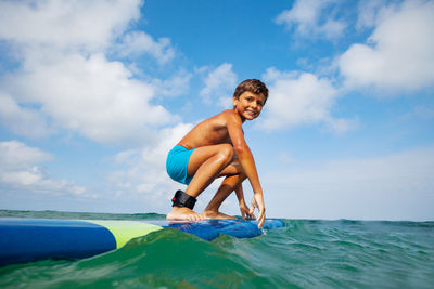 Portrait of shirtless man swimming in sea against sky