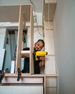 Building a wardrobe. man using framing nailer to attach wooden plywoods.