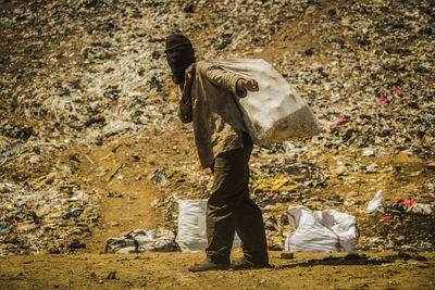 Man standing by garbage on field