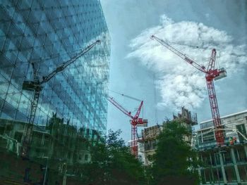 Low angle view of crane against cloudy sky