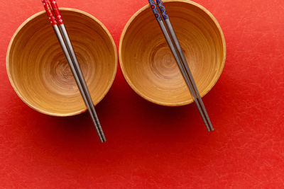 Directly above shot of bowls with chopsticks on red background