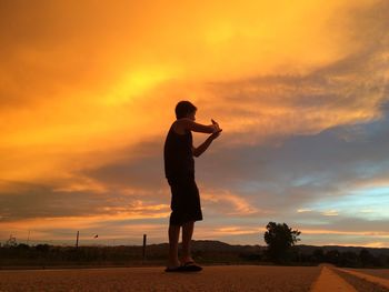 Silhouette of man standing on landscape at sunset