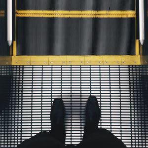 Low section of man standing on escalator