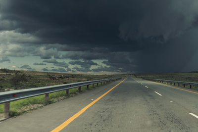 Empty road against cloudy sky