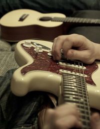 Midsection of man playing guitar