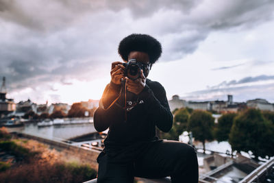 Man photographing against sky in city