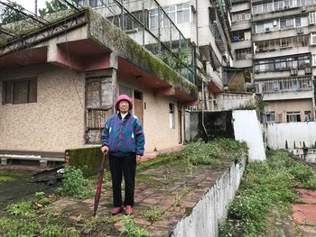 Portrait of woman standing against building