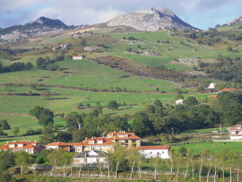 Houses on field by mountain against sky